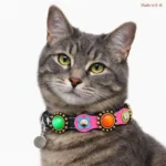 Modèle chat gris en angle avant portant le collier en cuir fait main, pierres colorées et patchs floraux, style fancy vibrant, fermeture élastique de sécurité et doublure douce.