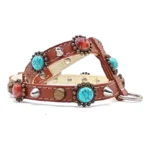 Braunes Leder­geschirr mit türkisfarbenen und rotbraunen Steinen in Messingfassungen, Messingstuds, silbernen Spikes und dekorativen Elementen, von links gesehen.