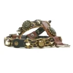 Brown and black leather dog harness with leopard‑print patches, ornate metal decorations, brass and silver studs and rounded spikes, shown from the left side.