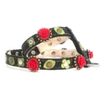 Harnais en cuir noir décoré de roses 3D rouge profond dans des ornements en laiton, fleurs et feuilles vertes en cuir, et studs en métaux mixtes, vu du côté gauche.