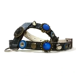 Black leather dog harness featuring blue stones in ornate settings, mixed‑metal studs, a single silver spike and detailed metal decorations, shown from the right side.