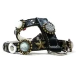 Schwarzes Leder­geschirr mit blau‑grau‑beigen funkelnden Steinen, weißen mondförmigen Lederpatches, goldenen Sternstuds und Metallelementen, von links gesehen.