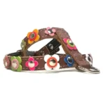 Harnais en cuir brun décoré de fleurs vintage multicolores et de clous argentés arrondis, vu du côté gauche.