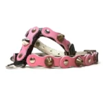 Black leather dog harness featuring a pink leather overlay with mixed metal studs and spikes, shown from the right side. The contrast between the black base and pink layer gives the harness a sweet but edgy style.