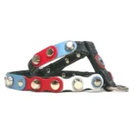 Harnais en cuir noir avec pièces rouge‑blanc‑bleu en mouvement fluide et clous argentés élégants, vu du côté gauche.