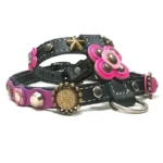 Harnais en cuir noir avec couture blanche, fleurs roses et violettes, clous dorés et argentés, vu du côté gauche.