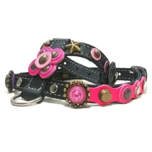 Harnais en cuir noir avec fleurs roses vives, accents violets, détail doré scintillant et clous métalliques, vu du côté droit.