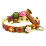Leather dog harness “Rosy Deluxe” in brown leather decorated with colorful layered flowers, 3D roses, ornate buttons, and white stitching, shown from the left side.