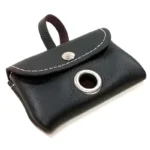 Black leather dog poop bag holder with stitching and metal grommet, shown from the front with bag ready to pull.