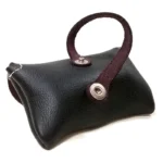 Close‑up of black leather poop bag holder’s rear strap and snap buttons.