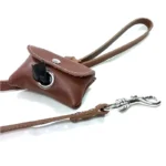 Bruine leren poepzakhouder bevestigd aan een lijn met een zakje dat door de opening is getrokken.